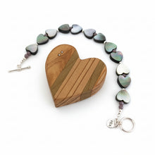 Load image into Gallery viewer, Bracelet with heart shaped beads accented by faceted tiny purple rondelles and sterling silver beads and clasp against a white background. Displayed along a wooden heart