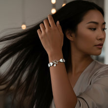 Load image into Gallery viewer, Woman wears on her upheld arm a shiny heart bracelet with sterling silver accents.
