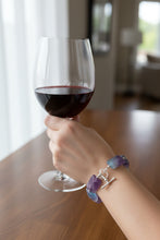 Load image into Gallery viewer, Woman holds glass of red wine showcasing bracelet of rectangular purple amethyst stones and sterling silver