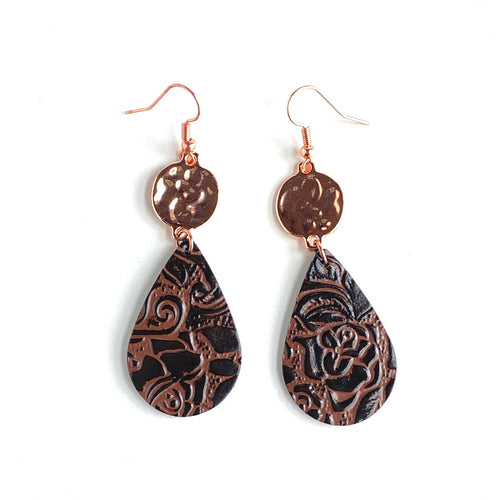 Brown Leather Earrings with etched roses hang from a flat, textured copper bead. Teardrop-shaped leather. Copper ear wires.  Collection: Leather Color: Brown, Copper Drop Length: 2 3/4 inch Material: Leather Metals: Copper-plate