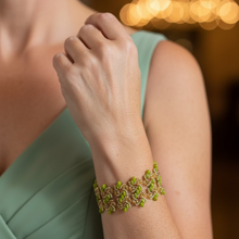 Load image into Gallery viewer, Close up of a beaded bracelet with green beads and gold and copper seedbeads on a formally dressed woman's arm.
