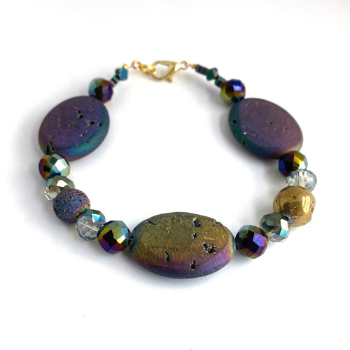Iridescent ovals that sparkle in shades of blue, purple, golds and greens are complemented by faceted glass and a solitary Golden Agate. 14K gold-plated lobster clasp make this diffuser bracelet both functional and elegant. Apply 1-2 drops of your favorite essential oil to the iridescent lava bead. Breathe and smile.  Type: Diffuser Clasp Bracelet Size: 7