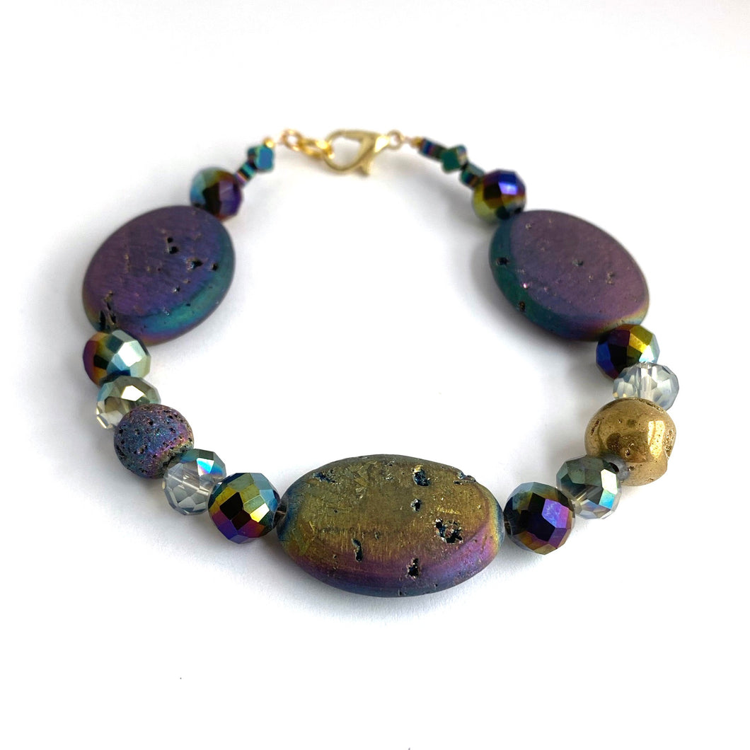Iridescent ovals that sparkle in shades of blue, purple, golds and greens are complemented by faceted glass and a solitary Golden Agate. 14K gold-plated lobster clasp make this diffuser bracelet both functional and elegant. Apply 1-2 drops of your favorite essential oil to the iridescent lava bead. Breathe and smile.  Type: Diffuser Clasp Bracelet Size: 7
